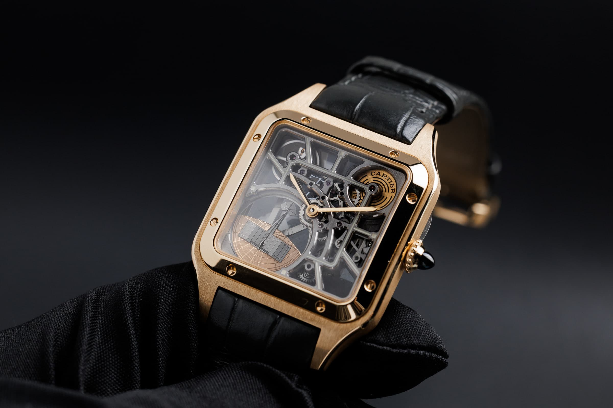 Cartier Santos-Dumont Skeleton WHSA0043 in gold, held in a gloved hand