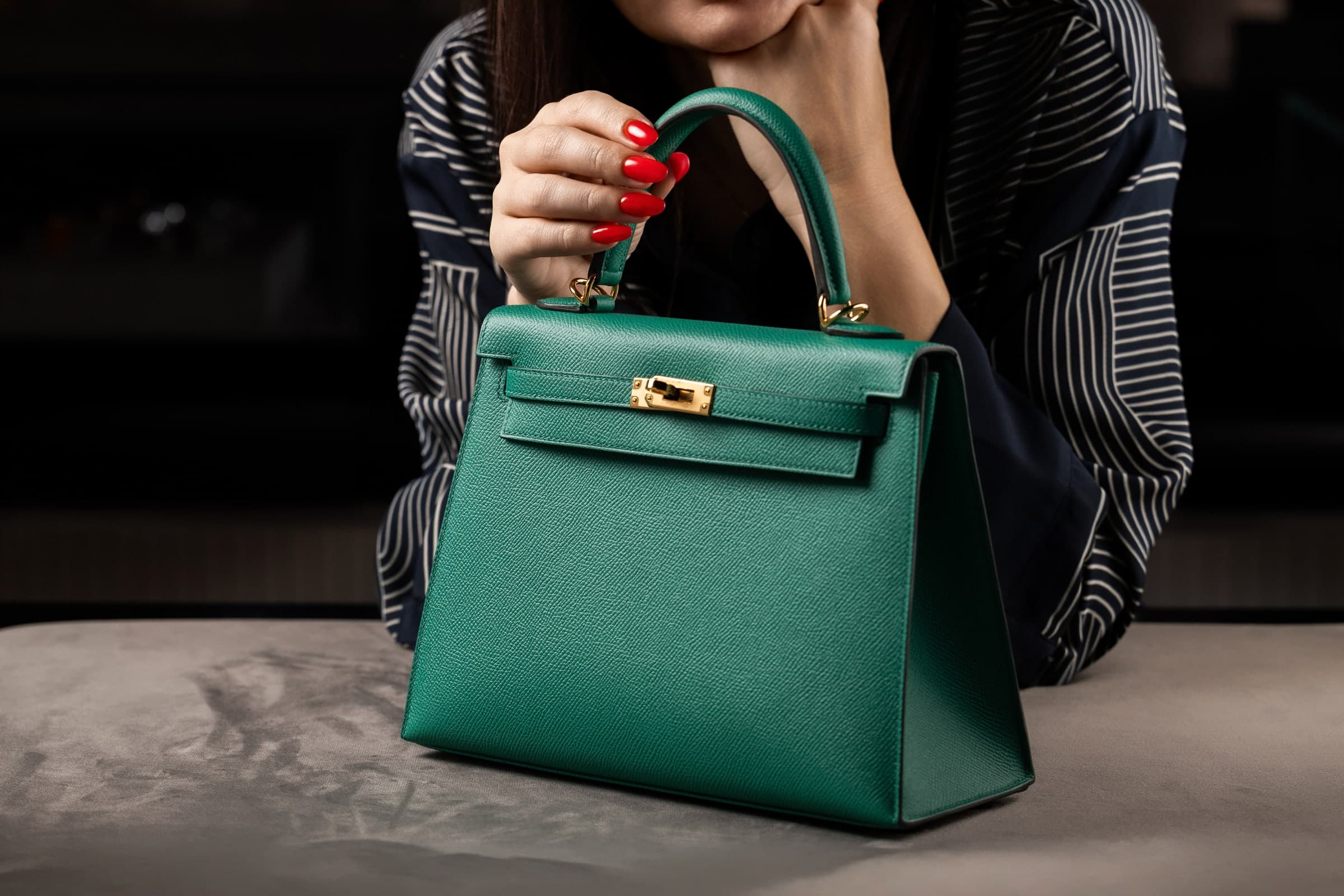 A Calliste specialist presenting a green Hermès Kelly to a client
